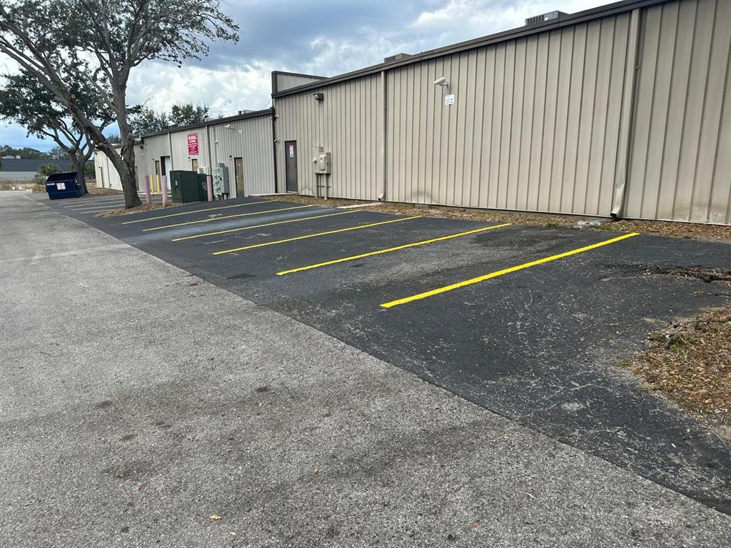 A paved parking area with yellow-painted lines sits beside a long, industrial metal-sided building — 1727 E BUSCH BOULEVARD, TAMPA, FL