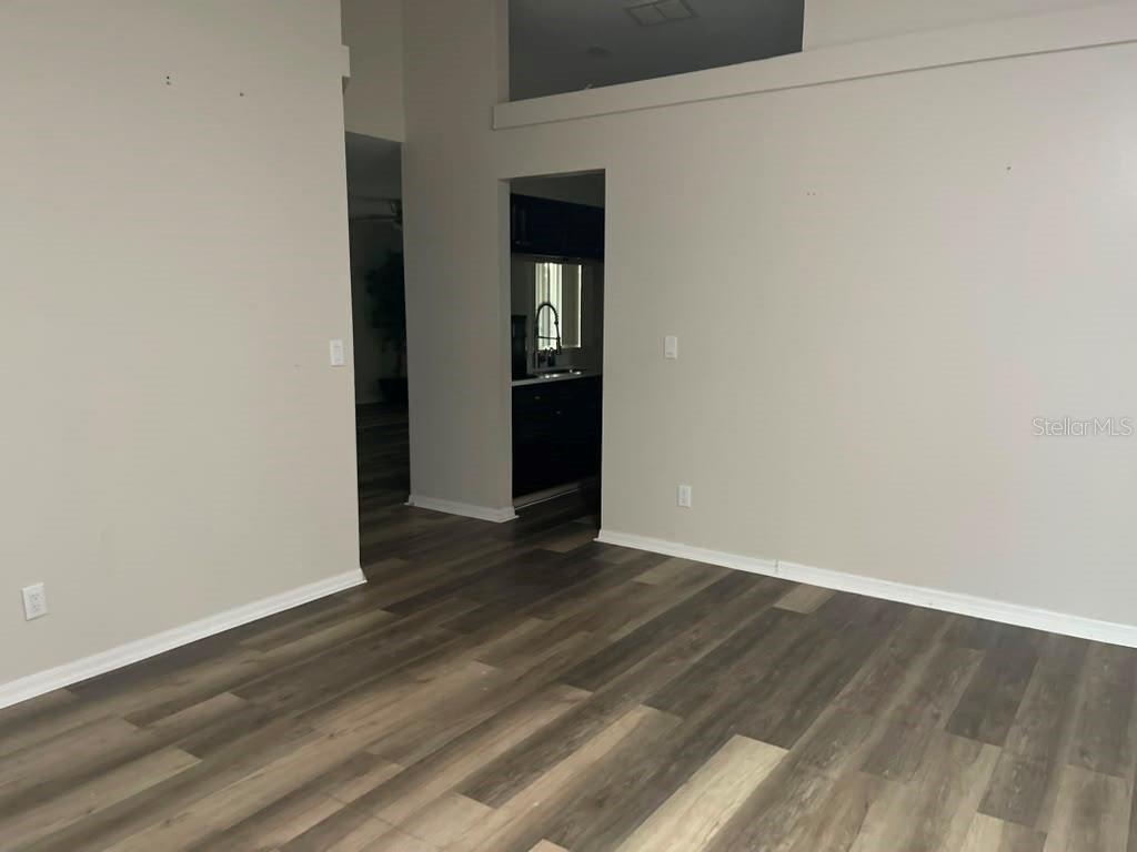 An interior view of a room with wood-look flooring and a doorway leading to a kitchen — 13303 PINYON DRIVE, CLERMONT, FL