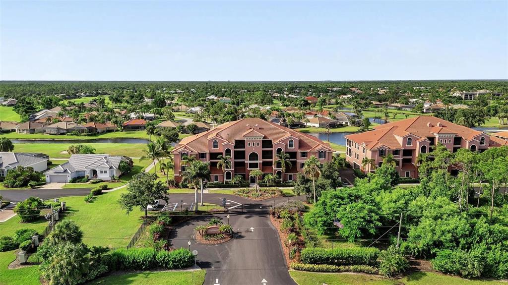 An aerial view shows two multi-story residential buildings surrounded by lush landscaping and a golf course — 24417 BALTIC AVENUE UNIT 1302, PUNTA GORDA, FL
