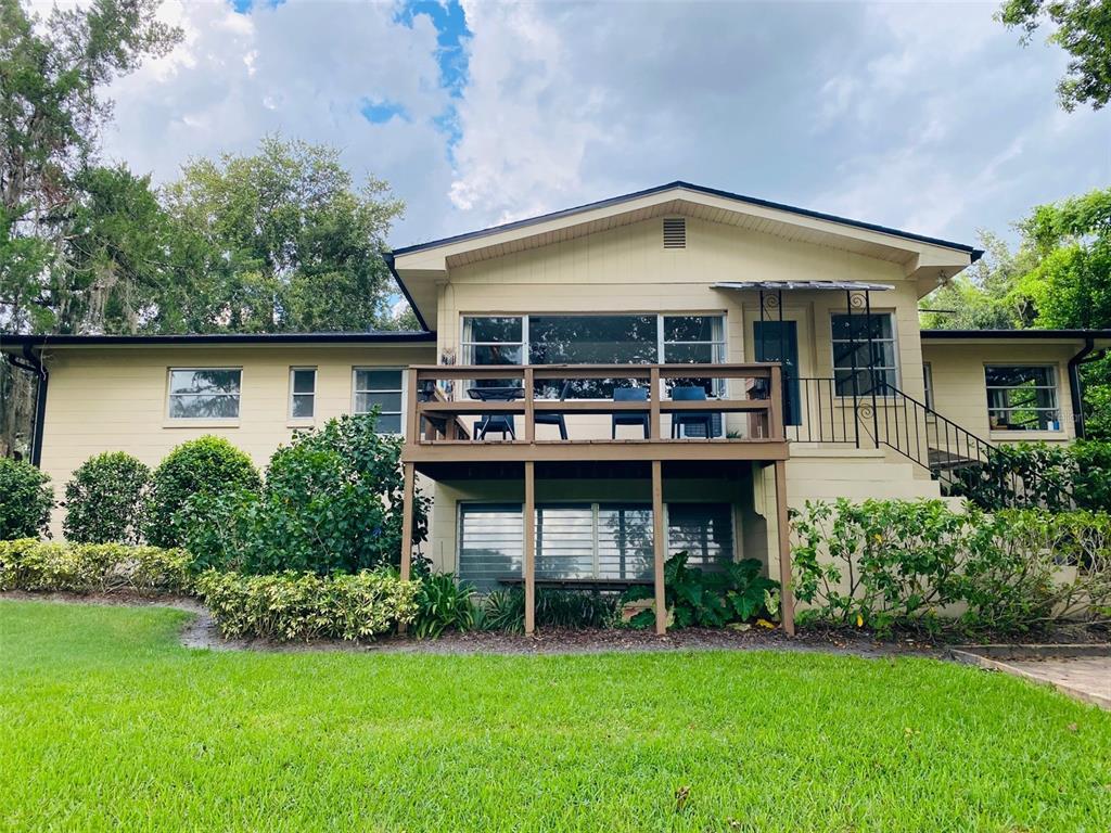 A two-story house with a wooden deck, light-colored siding, and a large grassy lawn — 1113 VIA DEL MAR, WINTER PARK, FL