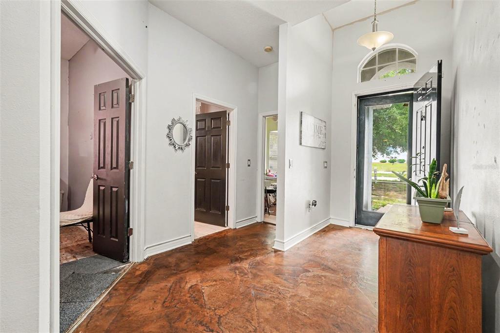 An entryway with stained concrete floors, a dark front door, and three interior doorways — 37110 HIGHLAND BLUFF CIRCLE, DADE CITY, FL