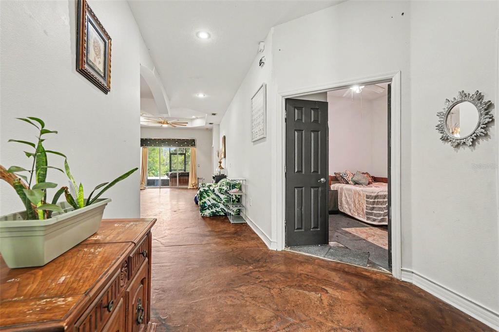 A hallway with stained concrete floors leads to a living area and a bedroom — 37110 HIGHLAND BLUFF CIRCLE, DADE CITY, FL