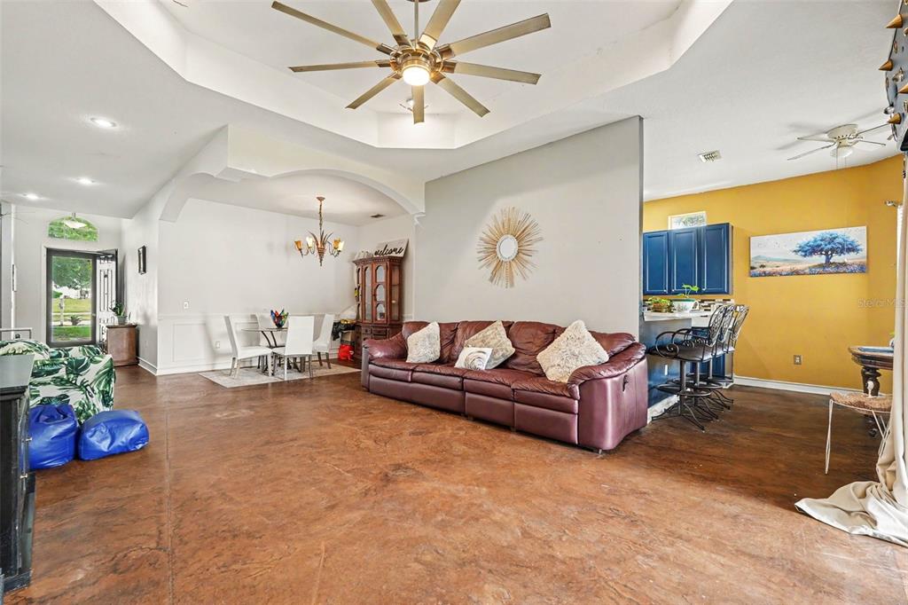A living room with a brown leather sofa, stained concrete floors, and an open kitchen — 37110 HIGHLAND BLUFF CIRCLE, DADE CITY, FL