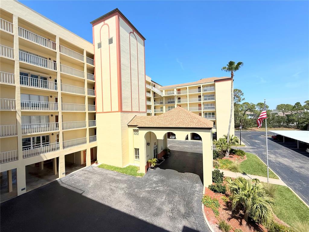 An exterior view of a multi-story apartment building featuring a covered entrance and parking lot — 9000 COMMODORE DRIVE UNIT 302, SEMINOLE, FL