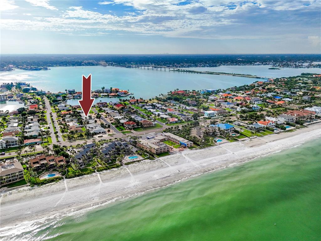An aerial view shows a coastal neighborhood with a red arrow pointing to a house — 107 21ST STREET, BELLEAIR BEACH, FL