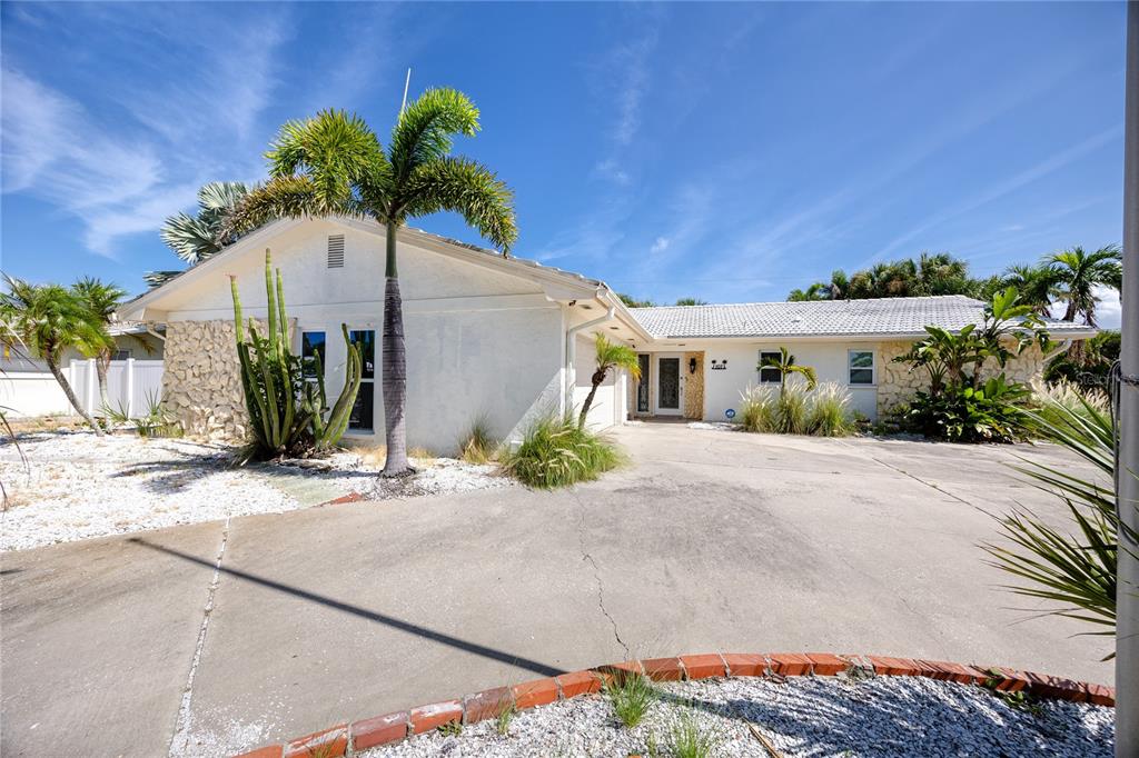 A single-story house with a white stucco facade, stone accents, and a concrete driveway — 107 21ST STREET, BELLEAIR BEACH, FL