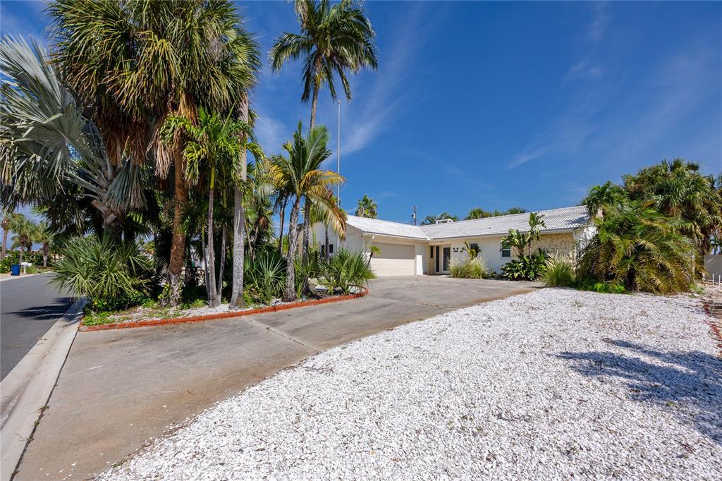 A single-story house with a white roof, concrete driveway, and palm trees in the yard — 107 21ST STREET, BELLEAIR BEACH, FL