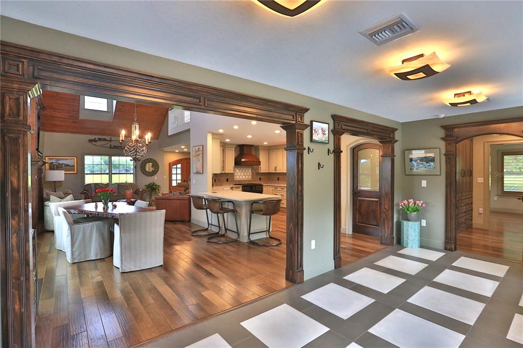 A view from a tiled foyer into a dining area and kitchen with wood flooring — 19650 NE 17TH PLACE, WILLISTON, FL