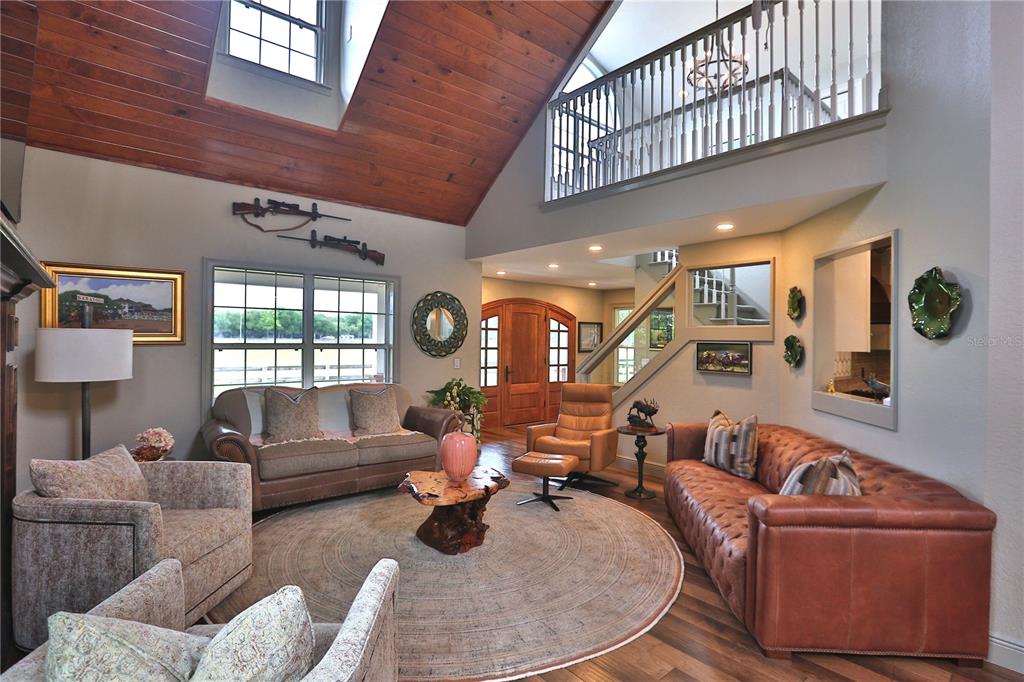 A living room features a vaulted wood ceiling, a loft balcony, and leather furniture — 19650 NE 17TH PLACE, WILLISTON, FL