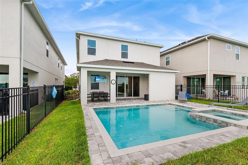 A two-story house exterior features a backyard swimming pool, a covered patio, and metal fencing — 416 SOUTHFIELD STREET, KISSIMMEE, FL
