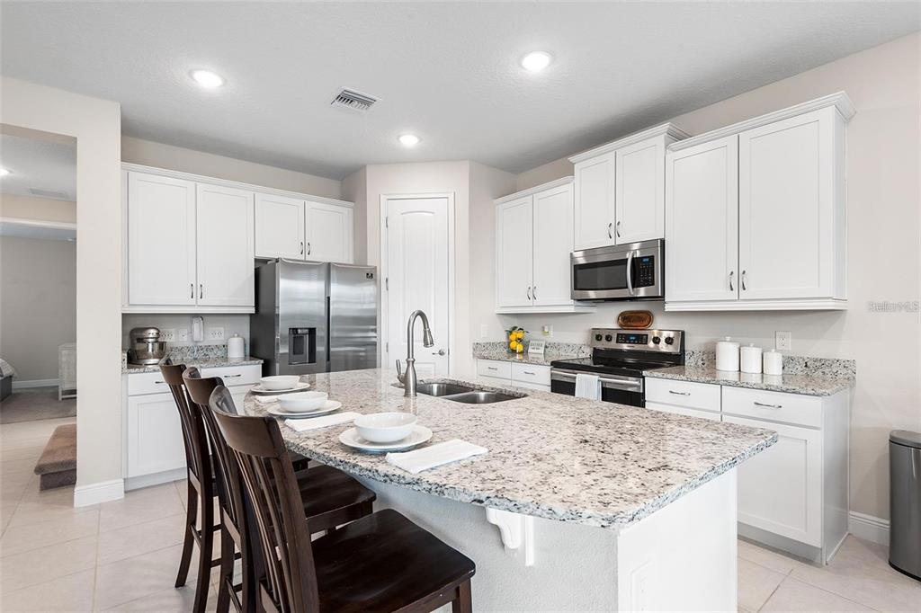 A kitchen with white cabinets, granite countertops, a center island, and stainless steel appliances — 416 SOUTHFIELD STREET, KISSIMMEE, FL