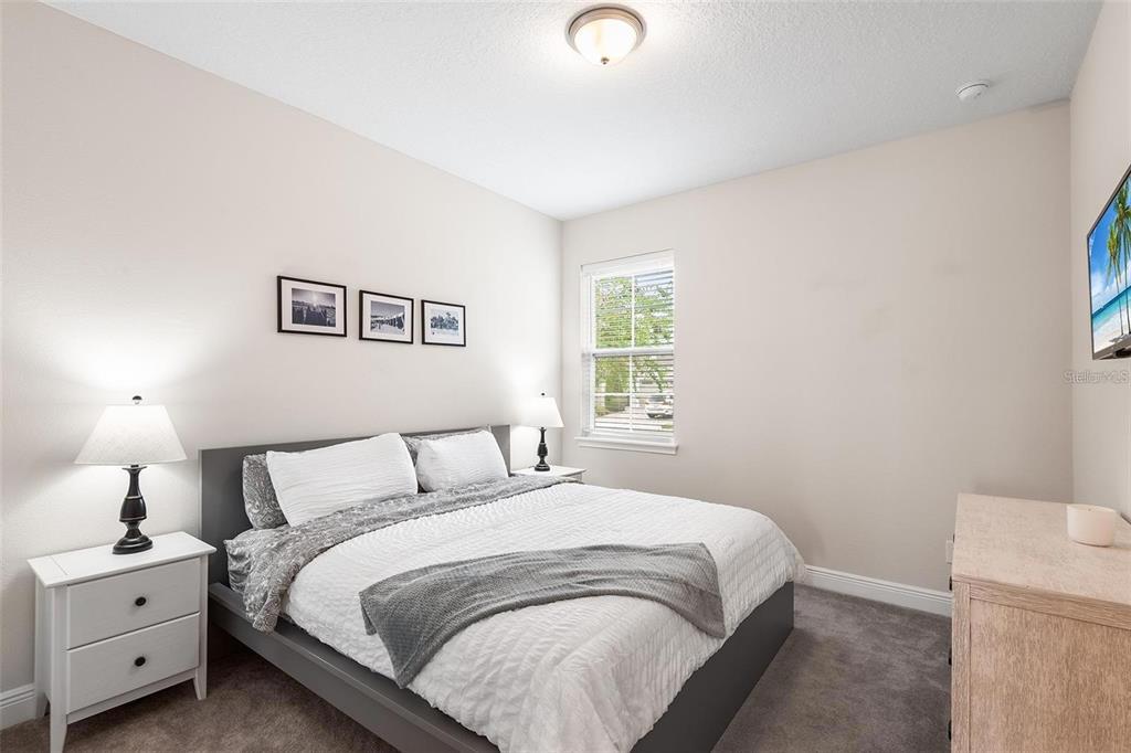 A bedroom features a gray bed frame, white bedding, two nightstands, and a window — 416 SOUTHFIELD STREET, KISSIMMEE, FL