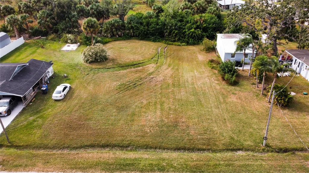 An aerial view shows a vacant grassy lot situated between two residential houses — CANAL, RUSKIN, FL