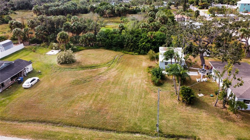 An aerial view shows a vacant grassy lot situated between two residential houses and trees — CANAL, RUSKIN, FL