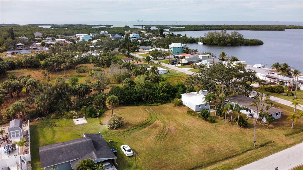 An aerial view shows a residential lot with a house, a shed, and nearby water — CANAL, RUSKIN, FL