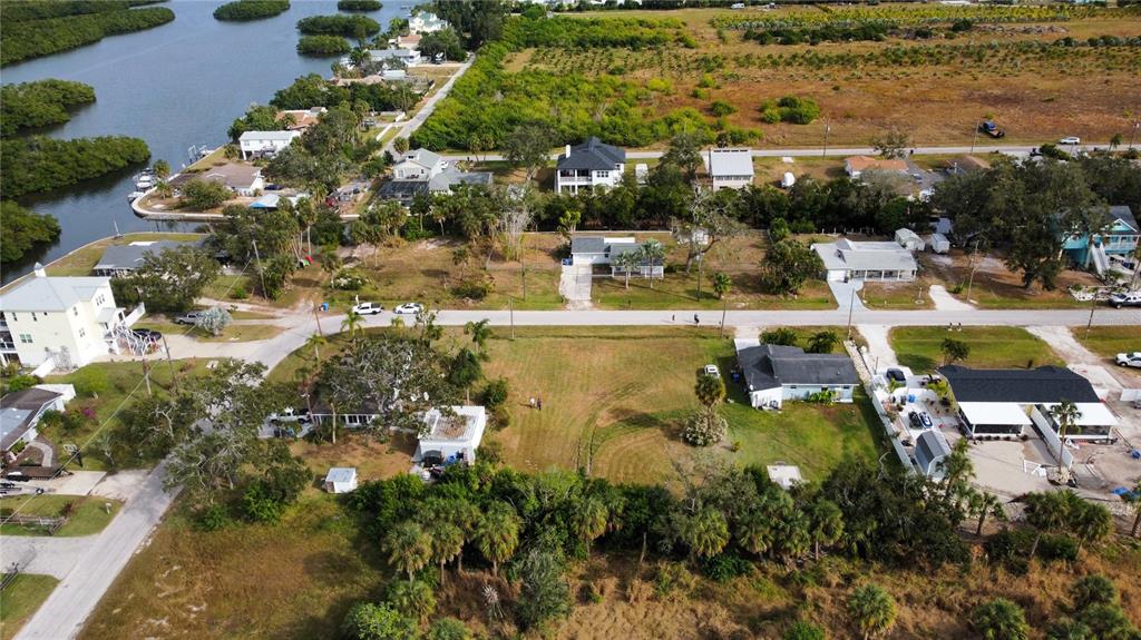 An aerial view shows a residential neighborhood with houses, vacant lots, and nearby waterways — CANAL, RUSKIN, FL