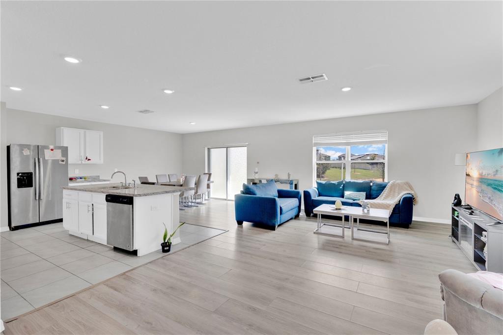 An open-concept living area features a kitchen with an island, dining space, and blue furniture — 167 EAGLEVIEW LOOP, DAVENPORT, FL