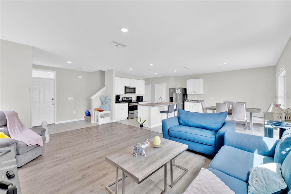 An open-concept living room and kitchen with light wood flooring and blue furniture — 167 EAGLEVIEW LOOP, DAVENPORT, FL