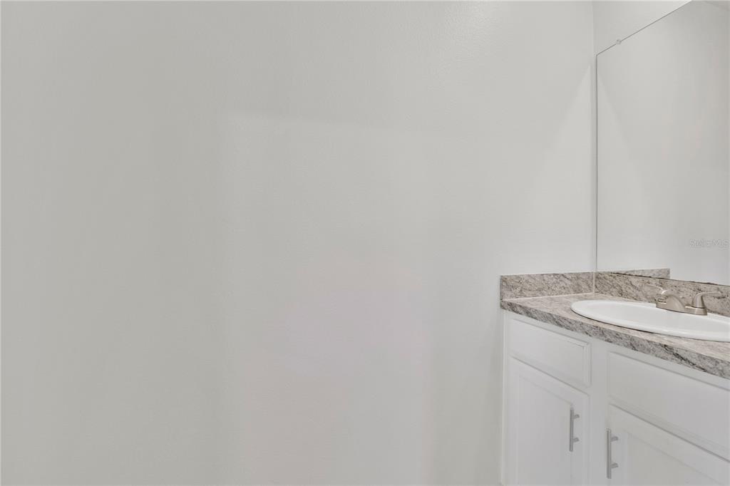 A bathroom features a white vanity with a granite countertop and a wall-mounted mirror — 167 EAGLEVIEW LOOP, DAVENPORT, FL