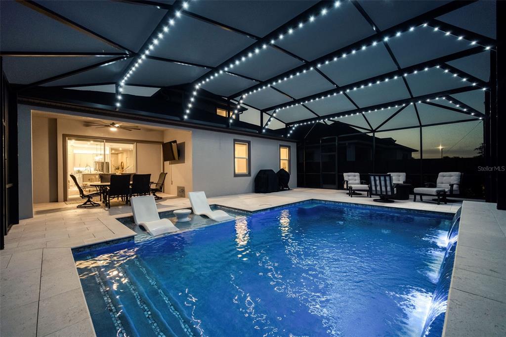 A swimming pool with lounge chairs and a water feature inside a screened-in patio — 13175 MCMILLAN, ORLANDO, FL