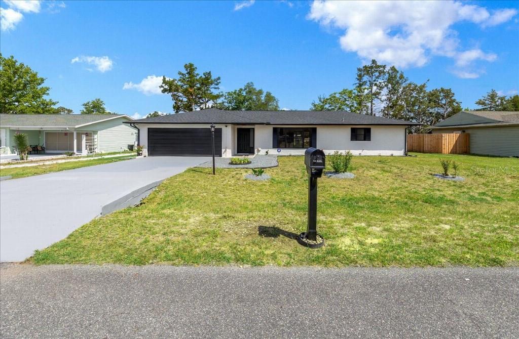 A single-story house with a black garage door, dark roof, and a front lawn — 59 SILVER PLACE, OCALA, FL