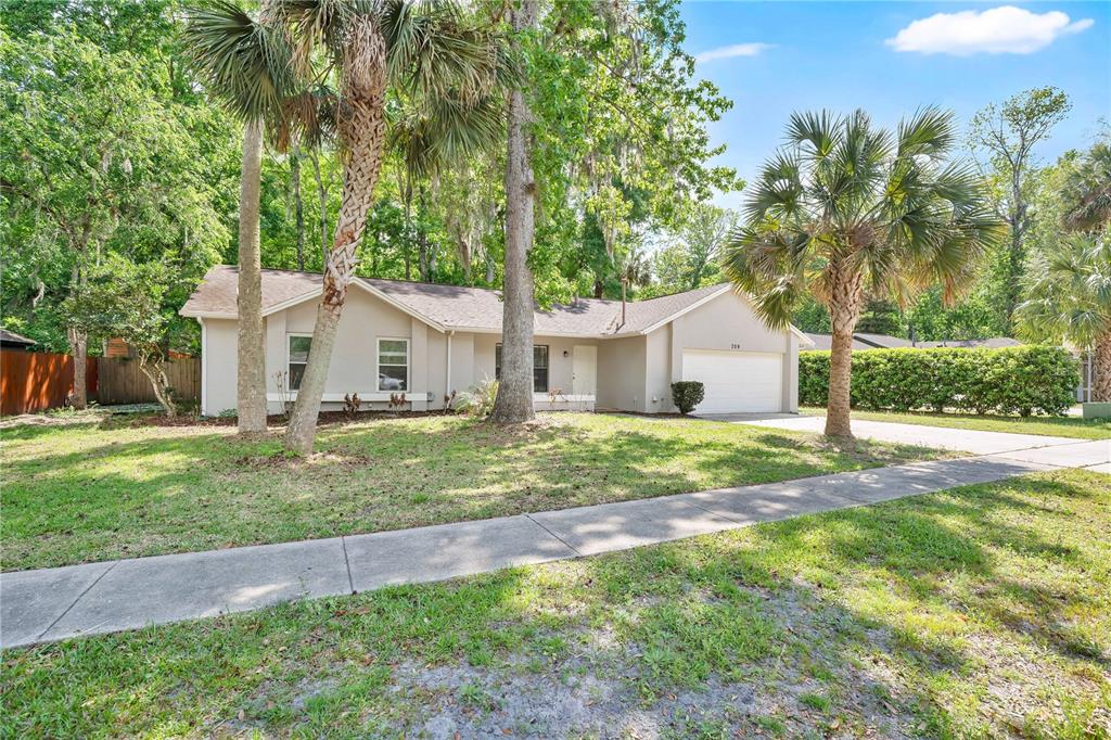 A single-story house with a beige exterior, a two-car garage, and palm trees in front — 709 SAILFISH ROAD, WINTER SPRINGS, FL