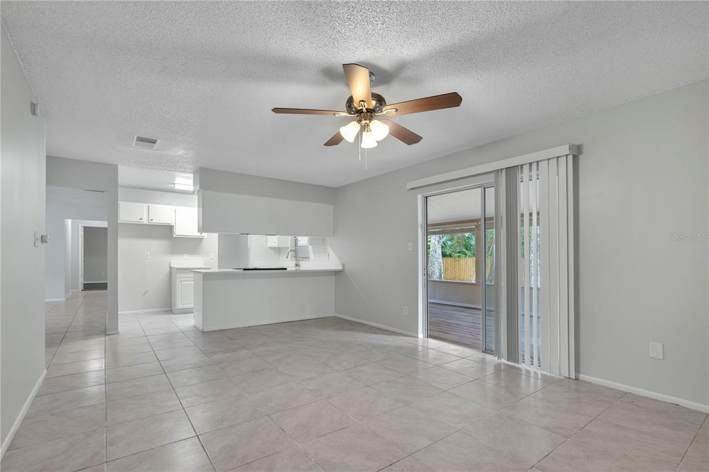 A living room with tile floors, a ceiling fan, and a sliding door to a patio — 709 SAILFISH ROAD, WINTER SPRINGS, FL