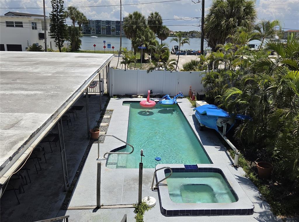 An elevated view shows a rectangular swimming pool and attached hot tub on a concrete patio — 580 BAY ESPLANADE, CLEARWATER BEACH, FL