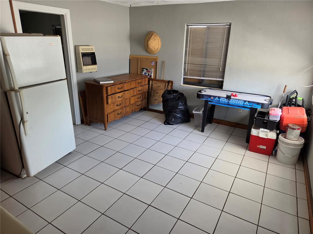 A room with white tile flooring, a refrigerator, a wooden dresser, and an air hockey table — 580 BAY ESPLANADE, CLEARWATER BEACH, FL