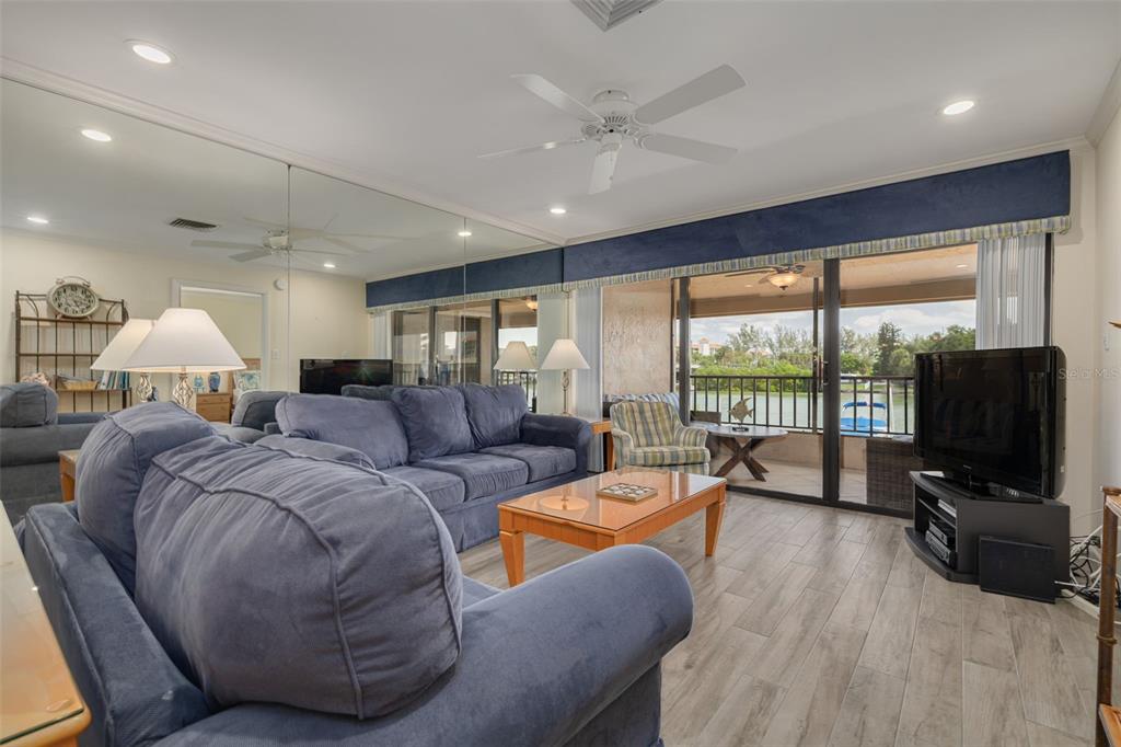 A living room features blue sofas, a wooden coffee table, mirrored walls, and a balcony view — 4780 BRITTANY DRIVE S UNIT 114, ST PETERSBURG, FL