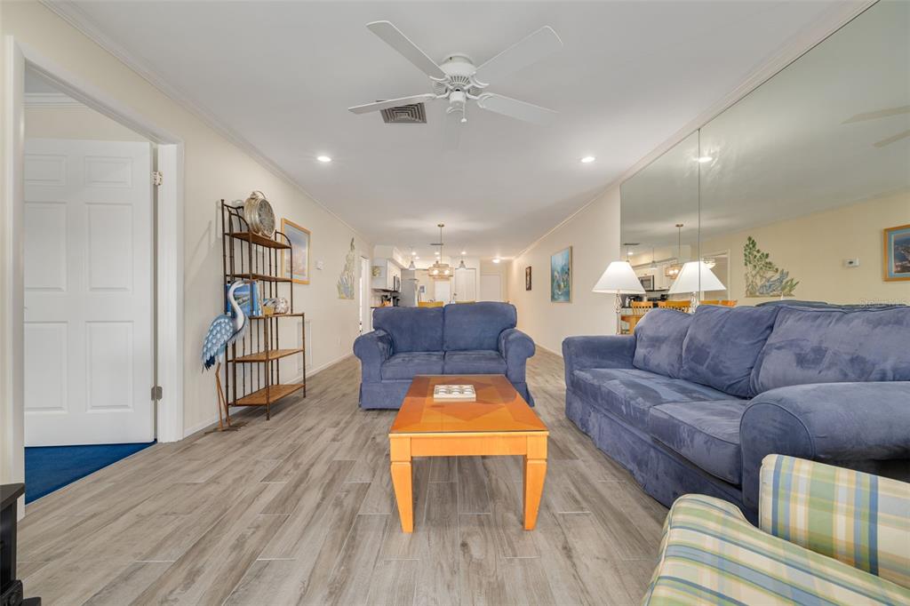 A living room features blue sofas, a wooden coffee table, and light wood-look flooring — 4780 BRITTANY DRIVE S UNIT 114, ST PETERSBURG, FL