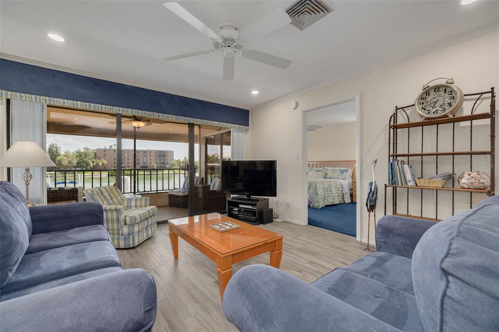 A living room features blue sofas, a wood coffee table, and a view of water — 4780 BRITTANY DRIVE S UNIT 114, ST PETERSBURG, FL