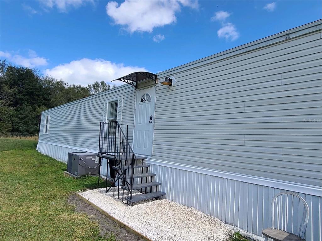 The exterior of a light-colored mobile home features a metal staircase leading to a door — 14626 MCGRADY ROAD, WIMAUMA, FL