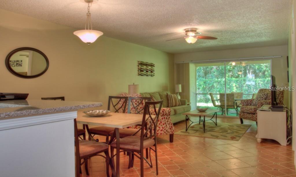A dining area and living room with tile floors, a ceiling fan, and sliding glass doors — 7062 W COUNTRY CLUB DRIVE N UNIT 7062, SARASOTA, FL