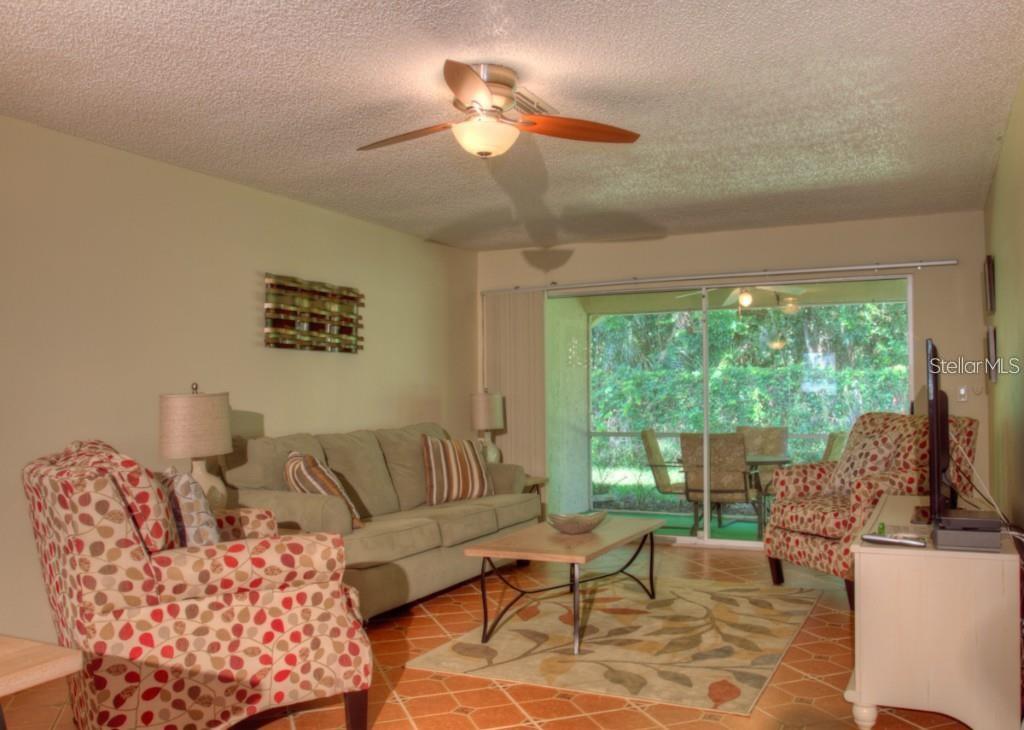 A living room with a beige sofa, patterned armchairs, a coffee table, and sliding glass doors — 7062 W COUNTRY CLUB DRIVE N UNIT 7062, SARASOTA, FL