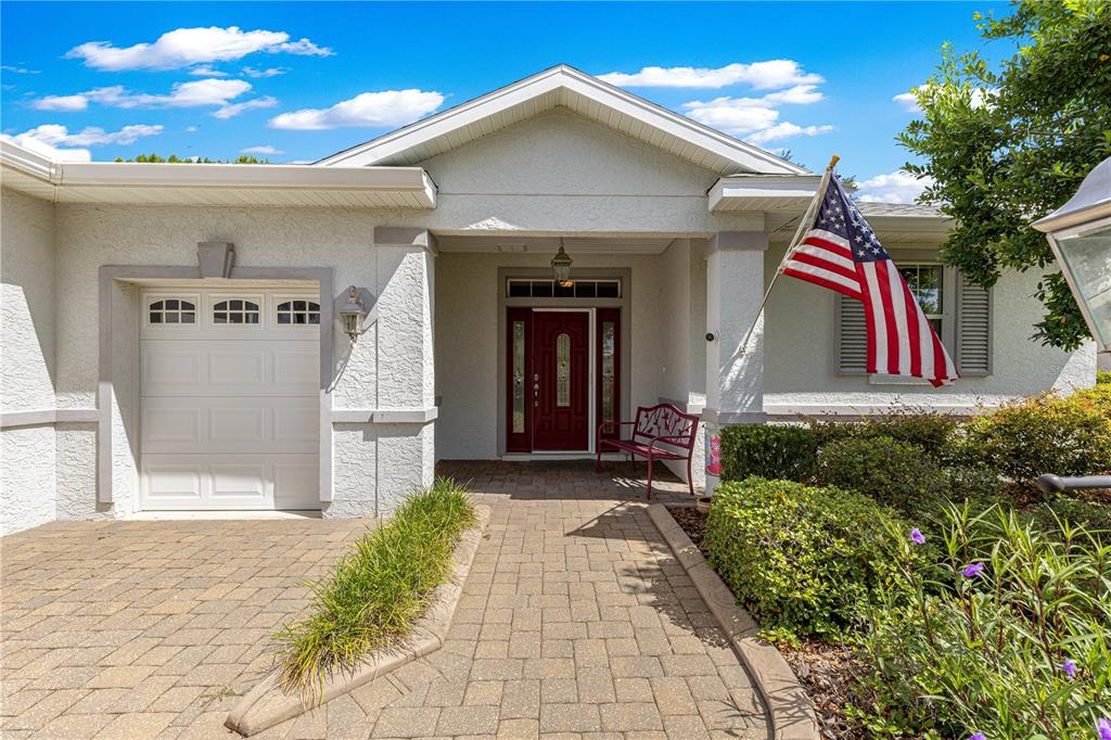 The exterior of a house features a paved walkway, a red front door, and an American flag — 8355 SW 84TH LOOP, OCALA, FL