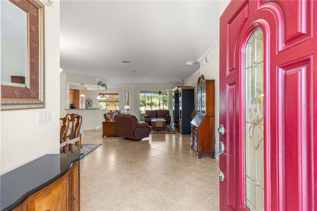 A view from an open red front door into a tiled living room and kitchen — 8355 SW 84TH LOOP, OCALA, FL