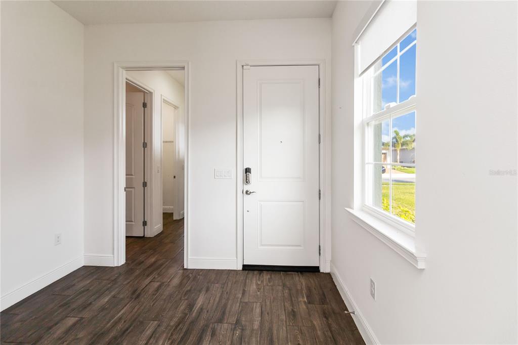 An entryway with dark wood-look flooring, a white front door, and a window — 2709 GREENLANDS STREET, ST CLOUD, FL