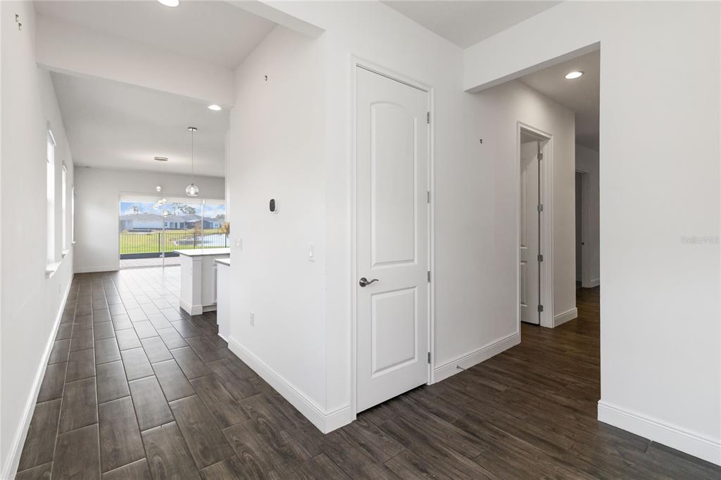 A hallway with dark wood-look tile flooring leads to an open kitchen and living area — 2709 GREENLANDS STREET, ST CLOUD, FL