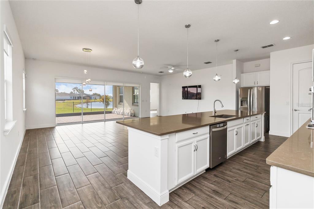 A kitchen with a large island, white cabinets, and tile flooring overlooks a backyard pond — 2709 GREENLANDS STREET, ST CLOUD, FL