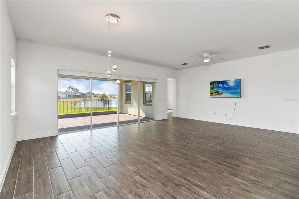 A living room with wood-look tile flooring, a ceiling fan, and sliding glass doors to a patio — 2709 GREENLANDS STREET, ST CLOUD, FL