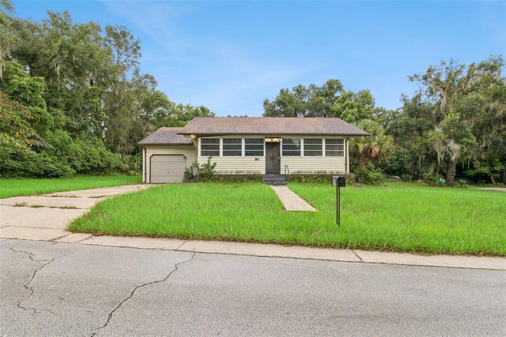 A single-story house with beige siding, a brown roof, and an attached garage — 381 W OHIO AVENUE, LAKE HELEN, FL