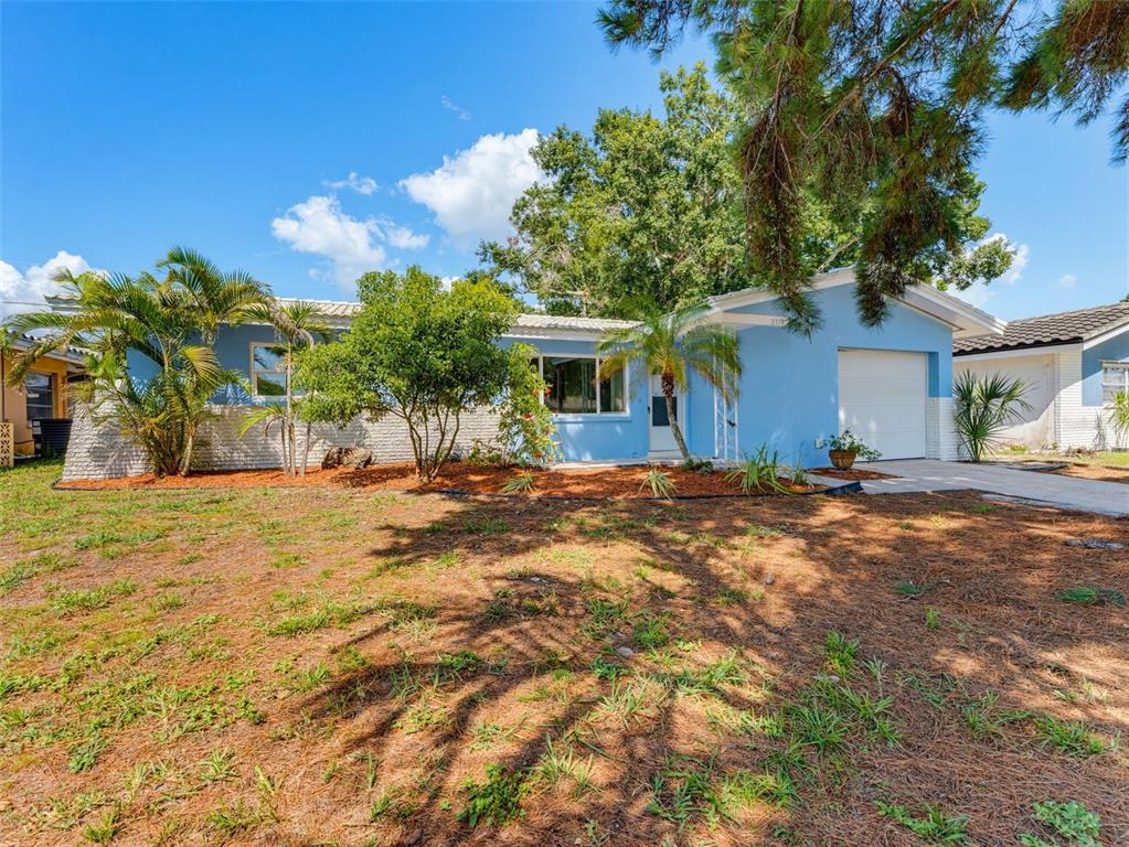 A single-story light blue house with a white garage and palm trees in the yard — 2373 FOREST DRIVE, CLEARWATER, FL