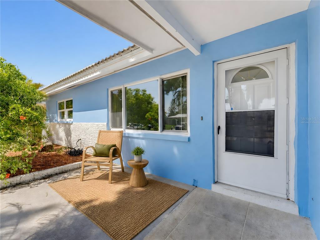 A light blue exterior wall features a white front door, windows, and a patio area — 2373 FOREST DRIVE, CLEARWATER, FL