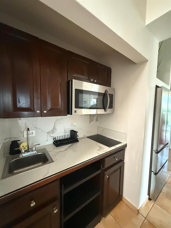 A small kitchen features dark wood cabinets, a stainless steel microwave, and a marble-patterned countertop — 170 Candelero Dr, PALMAS DEL MAR, LAS PALMAS DORADAS, HUMACAO, PR