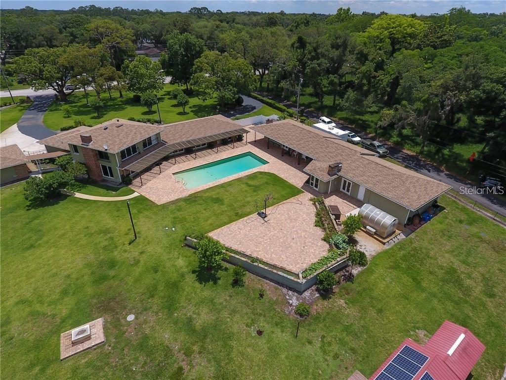 An aerial view shows a house with a swimming pool, patio, and large grassy yard — 910 N KEPLER ROAD, DELAND, FL