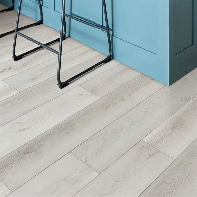 Light-colored wood-look flooring extends beneath a blue kitchen island and metal bar stools — 7027 161ST TERRACE E, PARRISH, FL