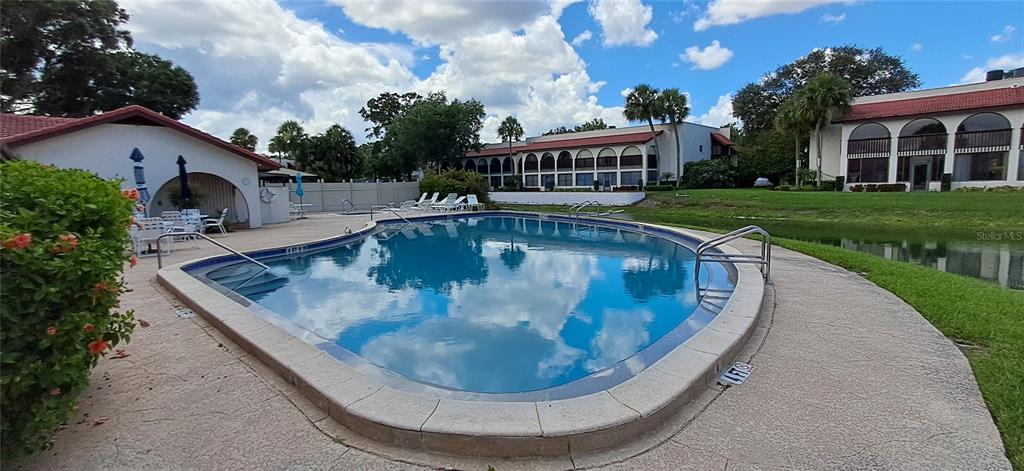 An outdoor swimming pool is surrounded by a concrete deck, landscaping, and multi-story residential buildings — 7201 COUNTRY CLUB DRIVE UNIT G21, LAKE WALES, FL