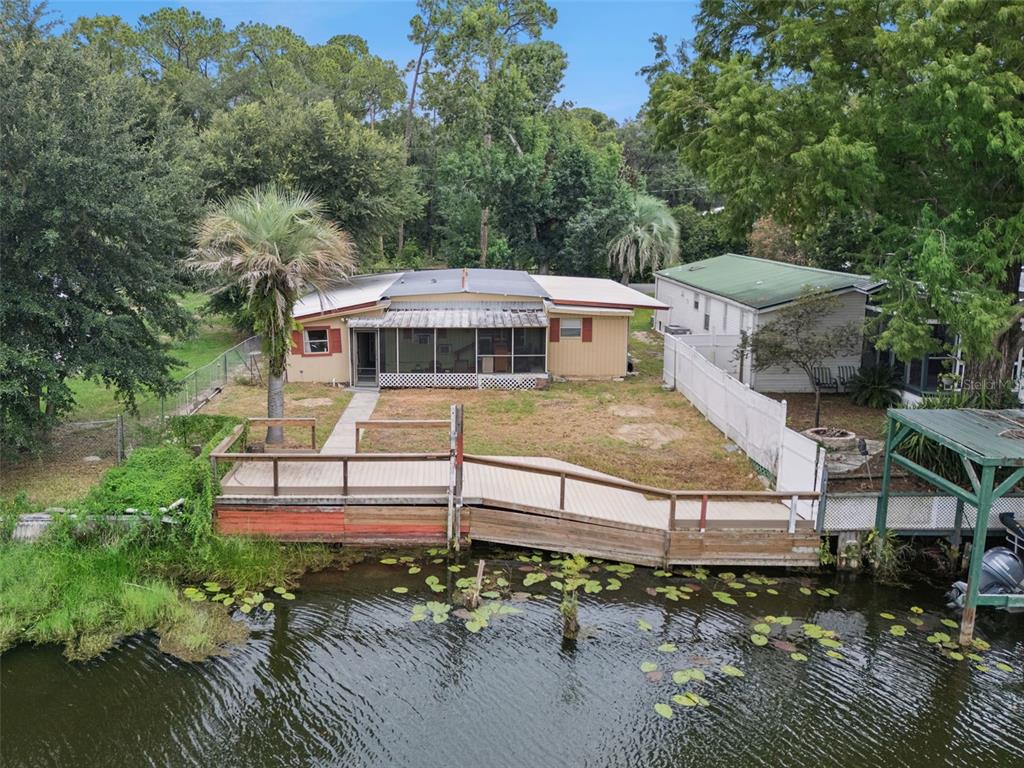 An aerial view of a waterfront house with a wooden deck and ramp leading to water — 13602 PALM DRIVE, ASTATULA, FL