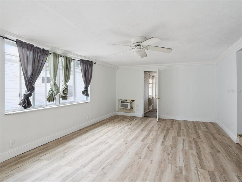 A room with white walls, light wood-look flooring, a ceiling fan, and a window unit — 13602 PALM DRIVE, ASTATULA, FL
